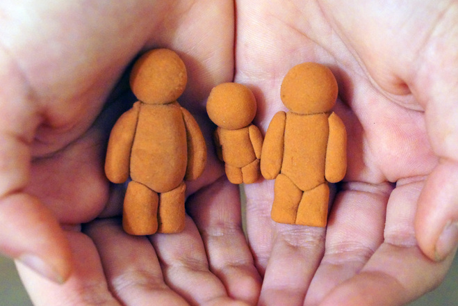 figures of a man, woman and child in children's hands, embodying the protection and preservation of family values